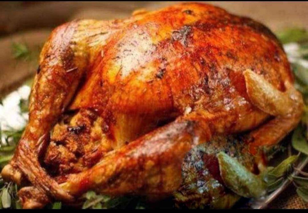Pavo entero horneado, dorado y servido sobre hierbas
