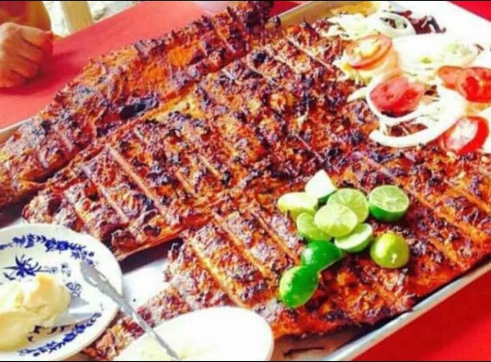 Pescado entero asado a las brasas con limones y ensalada de jitomate y cebolla